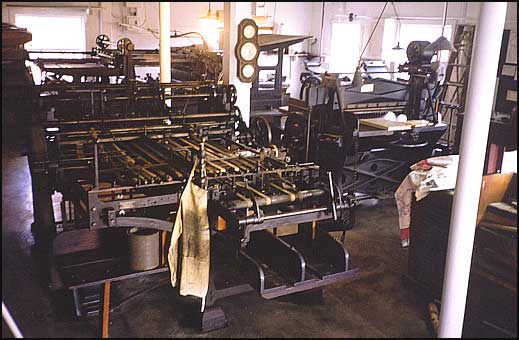 Interior of Printshop, center is a folding machine, the press in the rear is from 1891.